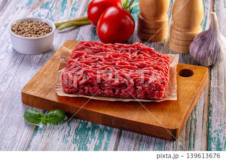 Fresh raw minced beef on a wooden board with cooking ingredients Fresh raw minced beef on a wooden board with cooking ingredients 139613676