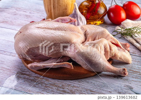 Raw duck carcass on a wooden cutting board with fresh ingredients for cooking 139613682