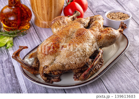 Whole roasted duck with crispy skin served on a plate with fresh vegetables and spices Whole roasted duck with crispy skin served on a plate with fresh vegetables and spices 139613683