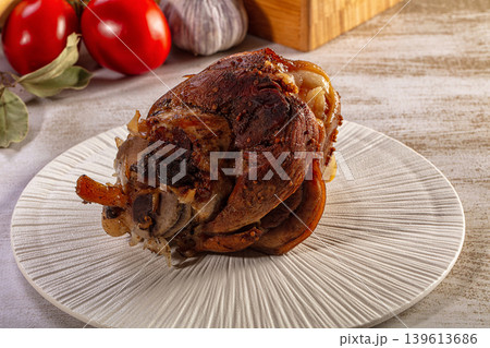 Roasted pork knuckle with crispy skin on a white plate with fresh vegetables 139613686