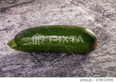 Single fresh green zucchini on a textured stone background Single fresh green zucchini on a textured stone background 139613698