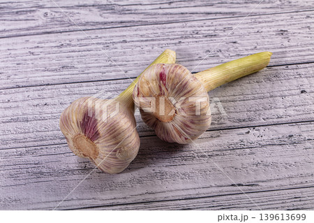 Two fresh garlic bulbs with purple streaks on a rustic wooden table Two fresh garlic bulbs with purple streaks on a rustic wooden table 139613699