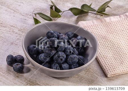 Ripe blueberries in ceramic bowl, scattered on rustic table with green leaves Ripe blueberries in ceramic bowl, scattered on rustic table with green leaves 139613709