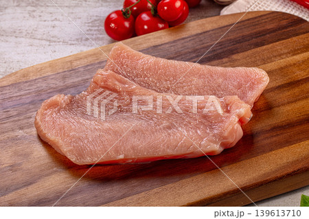 Raw turkey breast fillets on wooden cutting board with fresh cherry tomatoes, garlic, chili pepper, and basil Raw turkey breast fillets on wooden cutting board with fresh cherry tomatoes, garlic, chili pepper, and basil 139613710