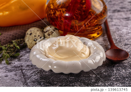Homemade mayonnaise sauce in white bowl with quail eggs and oil on dark table 139613745