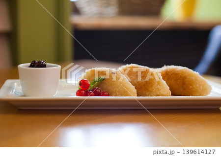 Sweet fried pastries with berry jam and redcurrant garnish on white plate Sweet fried pastries with berry jam and redcurrant garnish on white plate 139614127