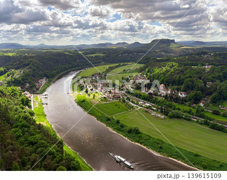 A panoramic, picturesque view of the Elbe River bend in the Saxon Switzerland National Park against a blue cloudy sky. A panoramic, picturesque view of the Elbe River bend in the Saxon Switzerland National Park against a blue cloudy sky. 139615109