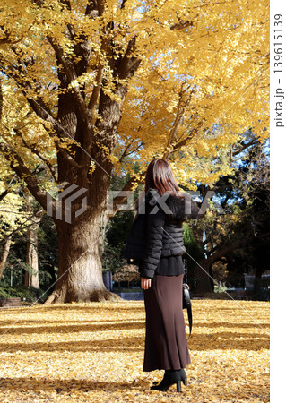 秋の公園でイチョウ並木を眺める女性の後ろ姿 139615139