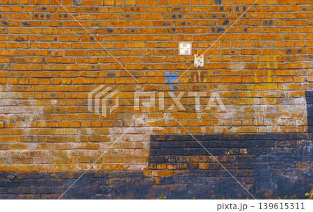 Weathered orange brick surface details. Close view of aged brick with markings and weathered features Weathered orange brick surface details. Close view of aged brick with markings and weathered features 139615311
