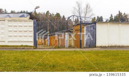 Fenced area with trees. Walled compound featuring functional facilities and natural greenery surroundings Fenced area with trees. Walled compound featuring functional facilities and natural greenery surroundings 139615335