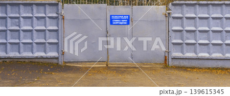 Residential compound features sturdy concrete fence with warning label and visible metal fastenings Residential compound features sturdy concrete fence with warning label and visible metal fastenings 139615345
