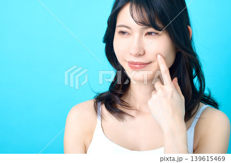 頬を指差して微笑む若い日本人女性 スキンケアイメージ 頬を指差して微笑む若い日本人女性 スキンケアイメージ 139615469