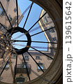 Interior view from a new roof window. Close up view of open roof window isolated with view of trees on blue sky and houses. 139615642