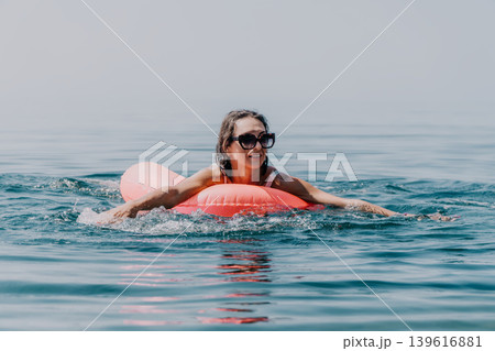 Woman floating relaxing on inflatable mattress in blue ocean water on sunny summer day 139616881