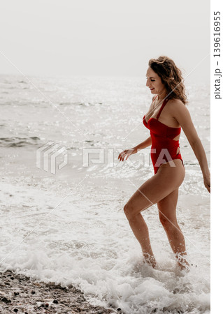 Woman Beach Swimsuit walking through the ocean surf during a happy summer vacation on a sunny coastline Woman Beach Swimsuit walking through the ocean surf during a happy summer vacation on a sunny coastline 139616955