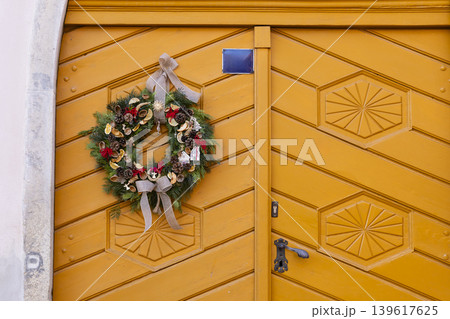 Christmas wreath decorating yellow wooden front door 139617625