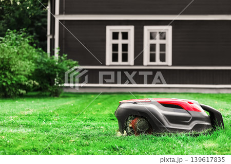 A modern robotic lawn mower automatically cuts grass.Ideal for smart home, eco-friendly gardening, and artificial intelligence themes. A modern robotic lawn mower automatically cuts grass.Ideal for smart home, eco-friendly gardening, and artificial intelligence themes. 139617835