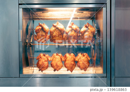 Grilling whole chickens in rotisserie machine,  front view . 139618863