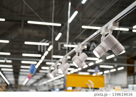 Ceiling-mounted track lighting with grey cylindrical spotlights. 139619016