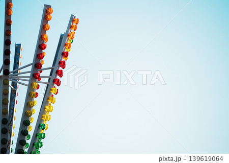 Abstract amusement park ride structure with colorful LED lights against a clear blue sky. Vibrant carnival ride details with red, yellow, and green lights and copy space for text. Abstract amusement park ride structure with colorful LED lights against a clear blue sky. Vibrant carnival ride details with red, yellow, and green lights and copy space for text. 139619064