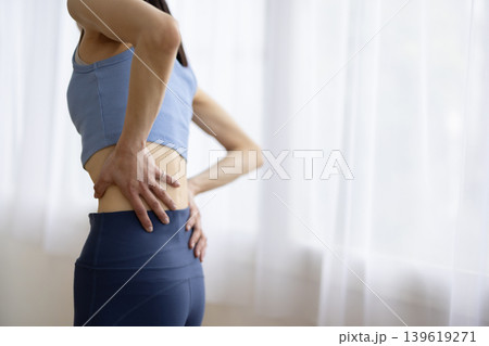 腰に手を当てて痛そうな表情をするヨガウェアを着た日本人のミドル女性 139619271