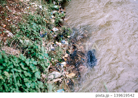 Dirty river filled with scattered waste and pollution Dirty river filled with scattered waste and pollution 139619542