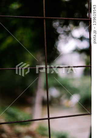 Rusty wire fence with blurred green background outdoors Rusty wire fence with blurred green background outdoors 139619543