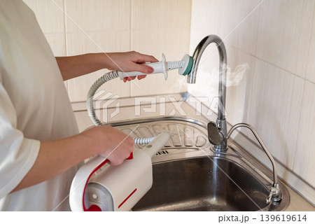 Cleaning the kitchen surface with a steam cleaner next to the sink at home 139619614