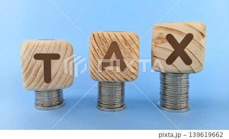 Tax concept with cube blocks or wooden blocks on top of a stack of coins. Economy and finance Tax concept with cube blocks or wooden blocks on top of a stack of coins. Economy and finance 139619662