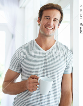 Man, coffee cup and portrait by window in morning with smile, relax or espresso with drink, choice or beverage in home. Person, tea and happy on holiday in house, apartment and latte to start day 139620188