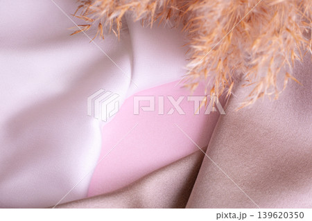 Abstract background in soft colors of silk fabrics on pink pearl paper and branch Dry beige reed. Beautiful trend texture Abstract background in soft colors of silk fabrics on pink pearl paper and branch Dry beige reed. Beautiful trend texture 139620350