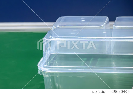 Close-up of clear plastic food container box parts moving on a conveyor belt in a high-standard manufacturing plant. 139620409