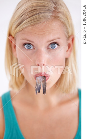 Eating, fish and portrait of woman with surprise and tail in mouth on white background of studio. Crazy, diet and hungry person with weird cuisine and seafood for sushil, nutrition and shocked face Eating, fish and portrait of woman with surprise and tail in mouth on white background of studio. Crazy, diet and hungry person with weird cuisine and seafood for sushil, nutrition and shocked face 139620416
