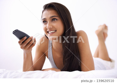 Happy woman, watching tv and relax on bed for entertainment, news or streaming at home. Face of young female person smile on weekend with remote for morning movie, series or shows lying in bedroom Happy woman, watching tv and relax on bed for entertainment, news or streaming at home. Face of young female person smile on weekend with remote for morning movie, series or shows lying in bedroom 139620510
