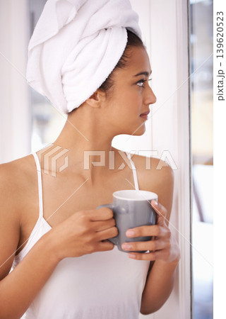 Woman, coffee and thinking in a home with nostalgia in the morning from hot drink and towel. Lounge, idea and relax Indian female person with espresso or tea in house ready to start the day at window Woman, coffee and thinking in a home with nostalgia in the morning from hot drink and towel. Lounge, idea and relax Indian female person with espresso or tea in house ready to start the day at window 139620523