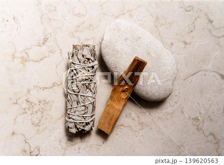 White sage bundle, palo santo stick on smooth stone on a light marble background White sage bundle, palo santo stick on smooth stone on a light marble background 139620563