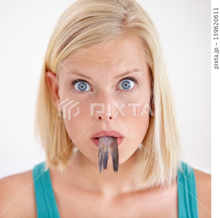 Portrait, woman and eating tail of fish with surprise and shock on white background of studio. Crazy, diet and person with taste of weird seafood, cuisine and disgust for gross or strange food 139620611