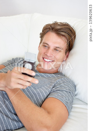 Phone, smile and man relax on a sofa with social media, chat or texting while streaming in his home. Smartphone, reading and male person search for online dating, meme or web, gif or subscription Phone, smile and man relax on a sofa with social media, chat or texting while streaming in his home. Smartphone, reading and male person search for online dating, meme or web, gif or subscription 139620633