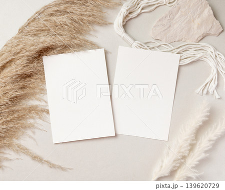 Blank portrait cards mockup in female hand over beige pampas grass top view, boho wedding stationery 139620729