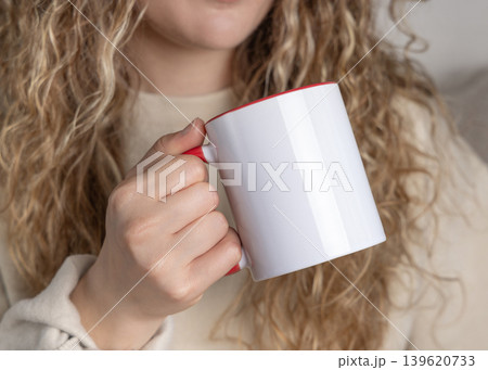 Blank white accented 11 oz coffee mug mockup in female hand, ceramic red handle cup template 139620733