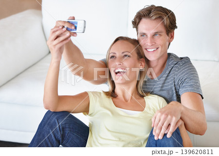 Love, selfie and couple hug in a living room for bonding, photography or memory in their home. Happy, photo or people embrace in a house with phone for social media, blog or profile picture update Love, selfie and couple hug in a living room for bonding, photography or memory in their home. Happy, photo or people embrace in a house with phone for social media, blog or profile picture update 139620811