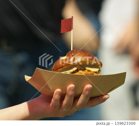 Customer holding street food burger in cardboard tray at festival Customer holding street food burger in cardboard tray at festival 139623300