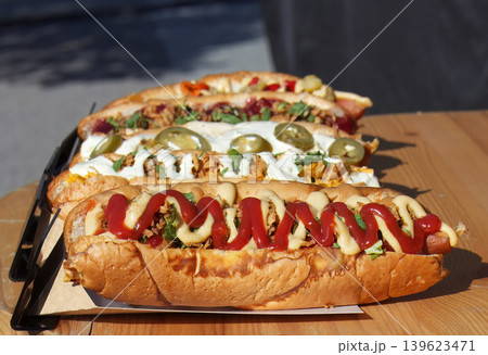Row of loaded gourmet hot dogs on wooden festival table 139623471