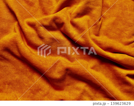 orange fabric crumpled into vibrant soft textured folds with intricate wrinkles and warm knit details orange fabric crumpled into vibrant soft textured folds with intricate wrinkles and warm knit details 139623629