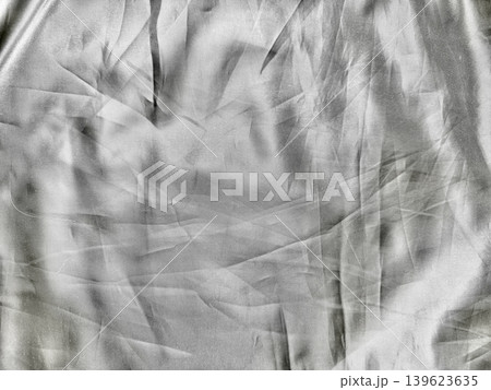 crumpled luminous silk fabric unveils intricate folds with dramatic shadows in abstract monochrome texture 139623635