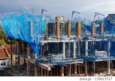 Building construction site with blue safety netting Building construction site with blue safety netting 139623727