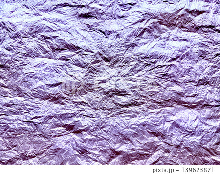 crumpled purple metallic foil shimmers revealing intricate dramatic wrinkles in abstract macro texture 139623871