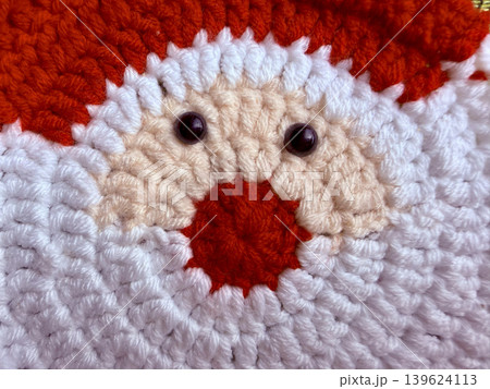 crocheted santa claus face with fluffy beard and red nose radiates jolly festive warmth through cozy handmade yarn crocheted santa claus face with fluffy beard and red nose radiates jolly festive warmth through cozy handmade yarn 139624113