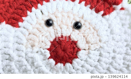 crocheted santa claus face with fluffy white beard and vibrant red nose black button eyes in cozy handmade yarn 139624114
