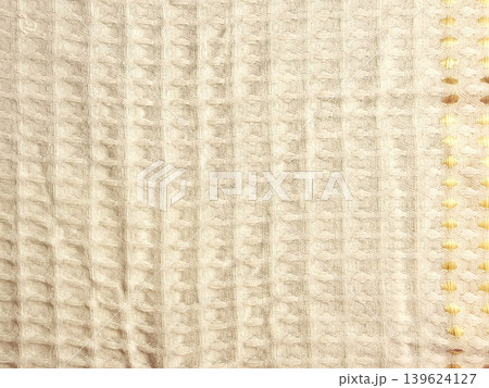 waffle weave soft cream fabric closeup revealing serene texture with intricate golden yellow honeycomb border detail 139624127